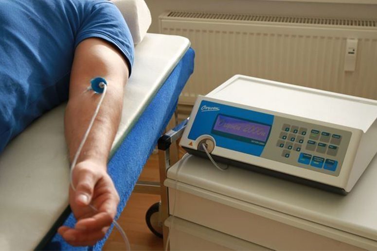 Person lying on a couch with a medical device connected to their arm via a catheter.